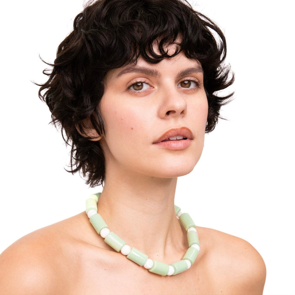 Woman wearing a light green beaded necklace on a white background