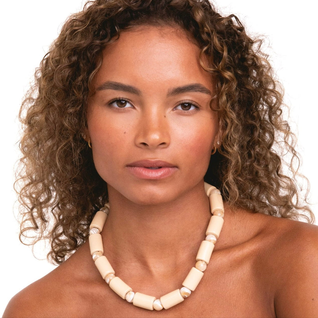 Woman wearing a necklace with a plain background