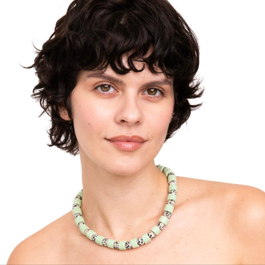 Woman wearing a light green beaded necklace against a white background
