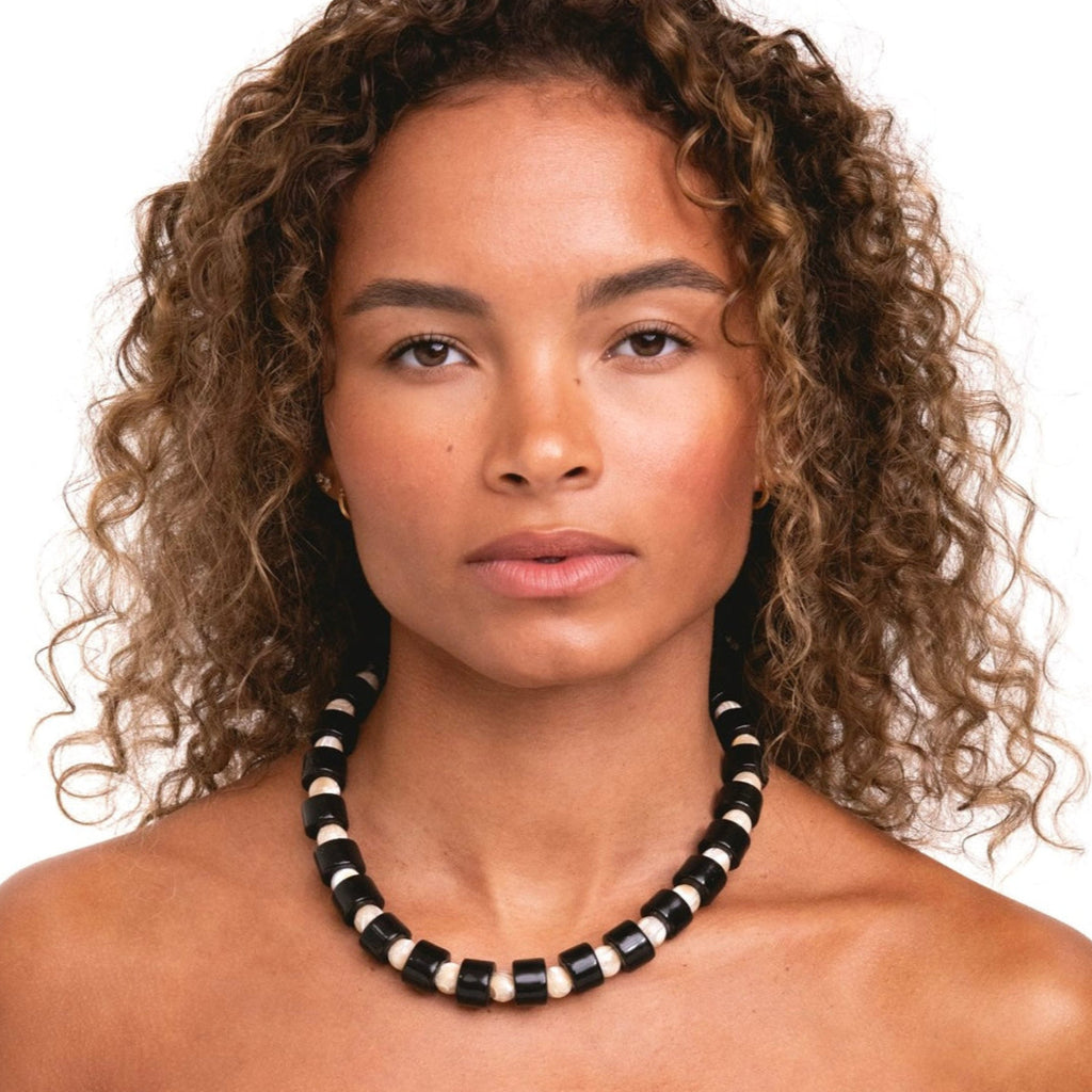 Woman wearing a black and white beaded necklace on a white background